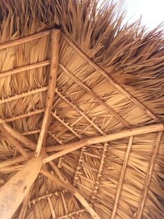 the roof of a straw hut with thatched roof and wooden poles on it's sides