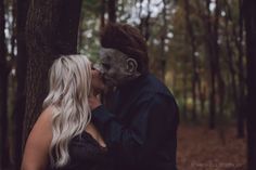 a man and woman are kissing in the woods with makeup on their faces as they stand next to each other