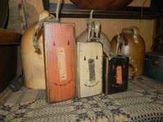 three wooden tags with faces on them sitting on a table next to pots and pans