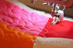 the sewing machine is on top of the pink and orange quilted material that has been sewn