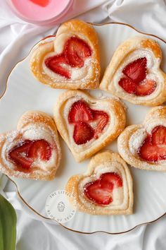 some heart shaped pastries on a plate with strawberries in the shape of hearts