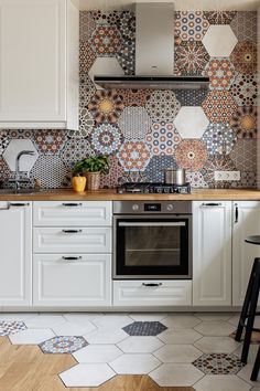 a kitchen with white cabinets and colorful tile backsplashes on the wall above the stove