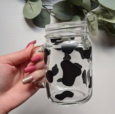 a hand holding a mason jar with black and white cow print