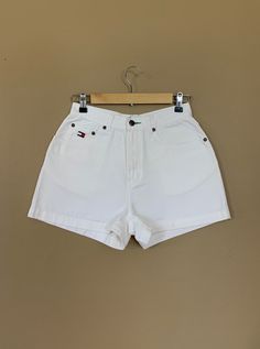 "High waisted 90's denim shorts. Made by Tommy Hilfiger in classic white denim wash with embroidered Tommy Hilfiger logo on back pocket. Shorts are in excellent clean condition with light naturally distressed character. Measurements (taken zipped or buttoned up and laid comfortably flat) inches x 2 for total circumference (inches) Tag Size 10 Tommy Hilfiger 100% Cotton Waist 27\" Hips 42\" Length 13.5\" Inseam 2.5\" Rise 11\" Bottom leg circumference 26\" All items are free of rips, tears, holes Vintage White Cotton Jean Shorts, Vintage White Jean Shorts For Spring, White Cotton Vintage Jean Shorts, White 90s Style Shorts For Summer, White 90s Style Summer Shorts, Classic High Waist Jean Shorts For Summer, Retro White Shorts With Pockets, Vintage White Jean Shorts, Vintage High Waist White Shorts