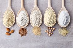 five wooden spoons filled with different types of nuts and grains on top of each other