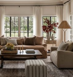 a living room filled with lots of furniture next to two windows and a coffee table