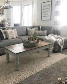 a living room with gray couches and pillows on the floor, coffee table in front of it