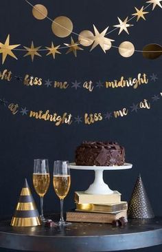 a cake and two wine glasses on a table with gold foil stars hanging from the ceiling