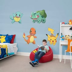 a young boy sitting on a bean bag chair in front of pokemon wall decals