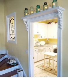 an open door leading to a kitchen with white cabinets and wooden steps in front of it