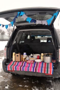 the back end of a car with an open trunk and food on it in the snow