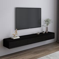 a flat screen tv mounted to the side of a wall next to a vase and potted plant