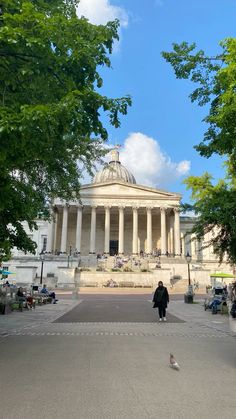 a person standing in front of a large building with columns and pillars on the side