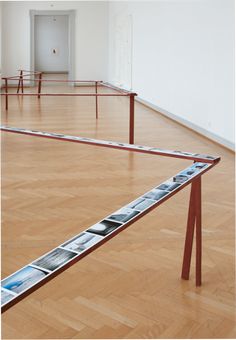 an empty room with wooden flooring and metal rails in the middle that have pictures on them