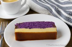 a piece of cake sitting on top of a white plate next to a cup of coffee