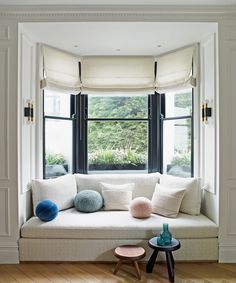 a white couch sitting under a window next to a table with two pom poms on it