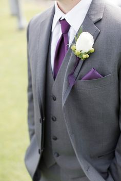 a man in a gray suit with a purple tie and white rose boutonniere