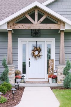 a front porch decorated for fall with wreaths and potted plants