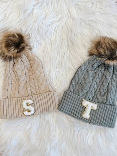 two knit hats with pom - poms on them