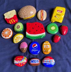 several different types of food and candy on a blue sheet with a black background, including an apple, watermelon, mcdonald's sandwich, donut, orange, macaroni - cheese, strawberry,