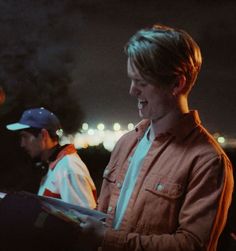 two young men standing next to each other in front of a city skyline at night