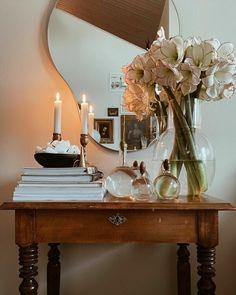 a vase filled with flowers sitting on top of a wooden table next to a mirror