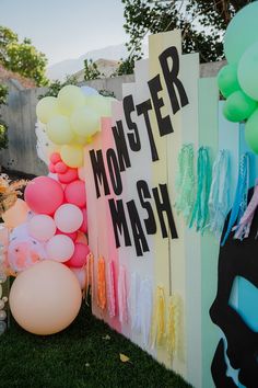 there is a monster mash sign on the fence with balloons attached to it,