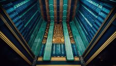 the inside of a building with blue and gold columns on it's sides, looking up at the ceiling