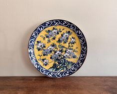 a yellow and blue plate sitting on top of a wooden table next to a wall