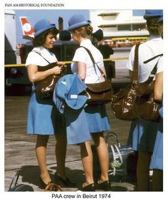 three women in uniforms are talking to each other on the tarmac at an airport