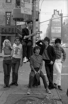 a group of young people standing on the side of a road next to a traffic light