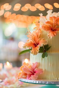 there is a cake with flowers on it and lit candles in the backround