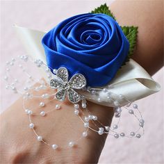 a wrist corsage with a blue rose and pearls on it's side