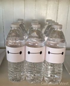 four water bottles with faces drawn on them sitting on top of a shelf next to each other