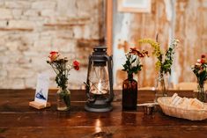 a table topped with vases filled with flowers next to a basket and candle holder