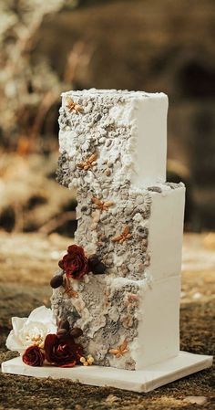 a three tiered white cake with flowers on it's side, sitting on top of a table