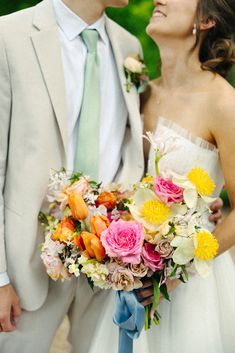 a bride and groom standing next to each other with flowers in their bouquet on their wedding day