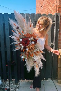 a woman holding a bouquet of flowers and feathers