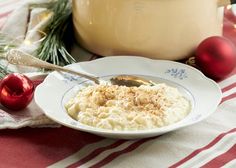 a bowl of mashed potatoes on a plate with a spoon and christmas decorations in the background