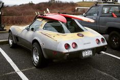 a car with a surfboard on the roof parked in a parking lot