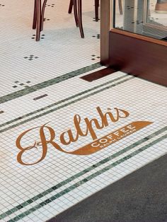 an image of a coffee shop sign on the ground in front of some tables and chairs