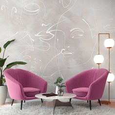 two pink chairs sitting next to each other in front of a wall with abstract designs on it