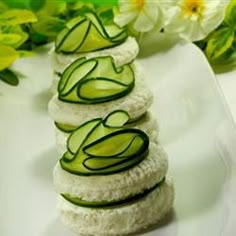 cucumber slices are stacked on top of each other on a white plate with flowers in the background