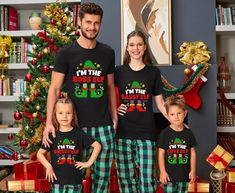 a family wearing matching christmas pajamas and matching t - shirts in front of a christmas tree