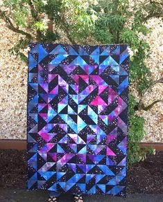 a woman standing next to a colorful quilt