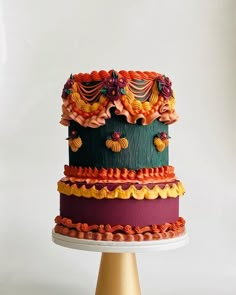 a multi - tiered cake with colorful decorations on top sits on a stand against a white background