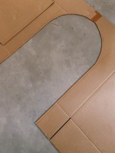 an open cardboard box on the ground with a piece of paper cut out to look like a circle