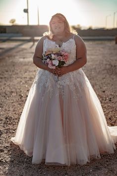 a woman is standing in the middle of a dirt field wearing a dress with flowers on it