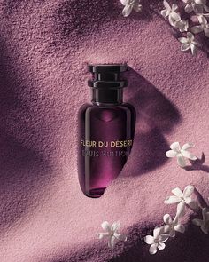 a bottle of perfume sitting on top of a purple surface with white flowers around it