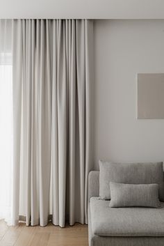 a couch sitting in front of a window next to a wall with curtains on it